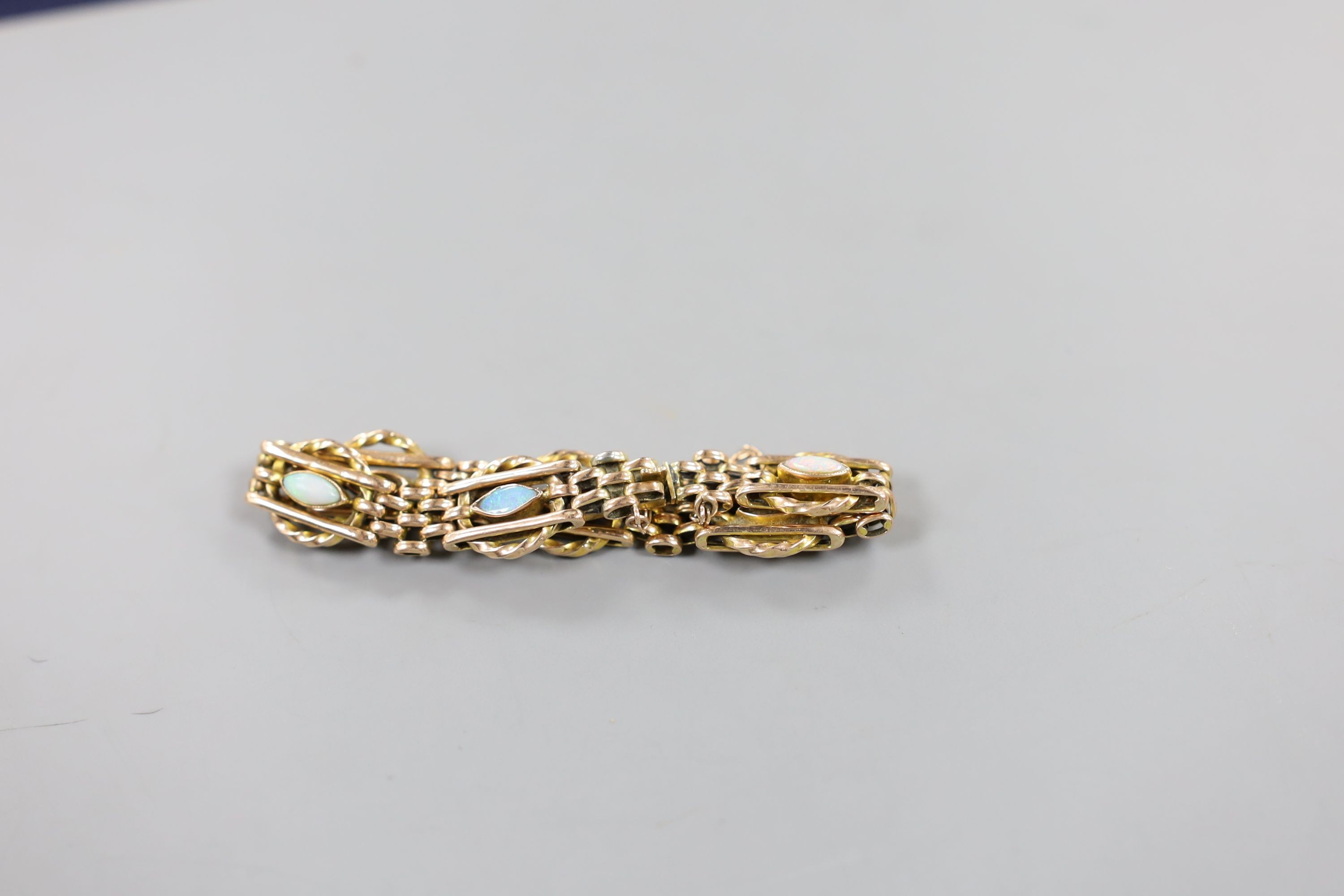 An Edwardian yellow metal and six stone navette shaped white opal set bracelet, with safety chain, 15cm, gross weight 10.6 grams.